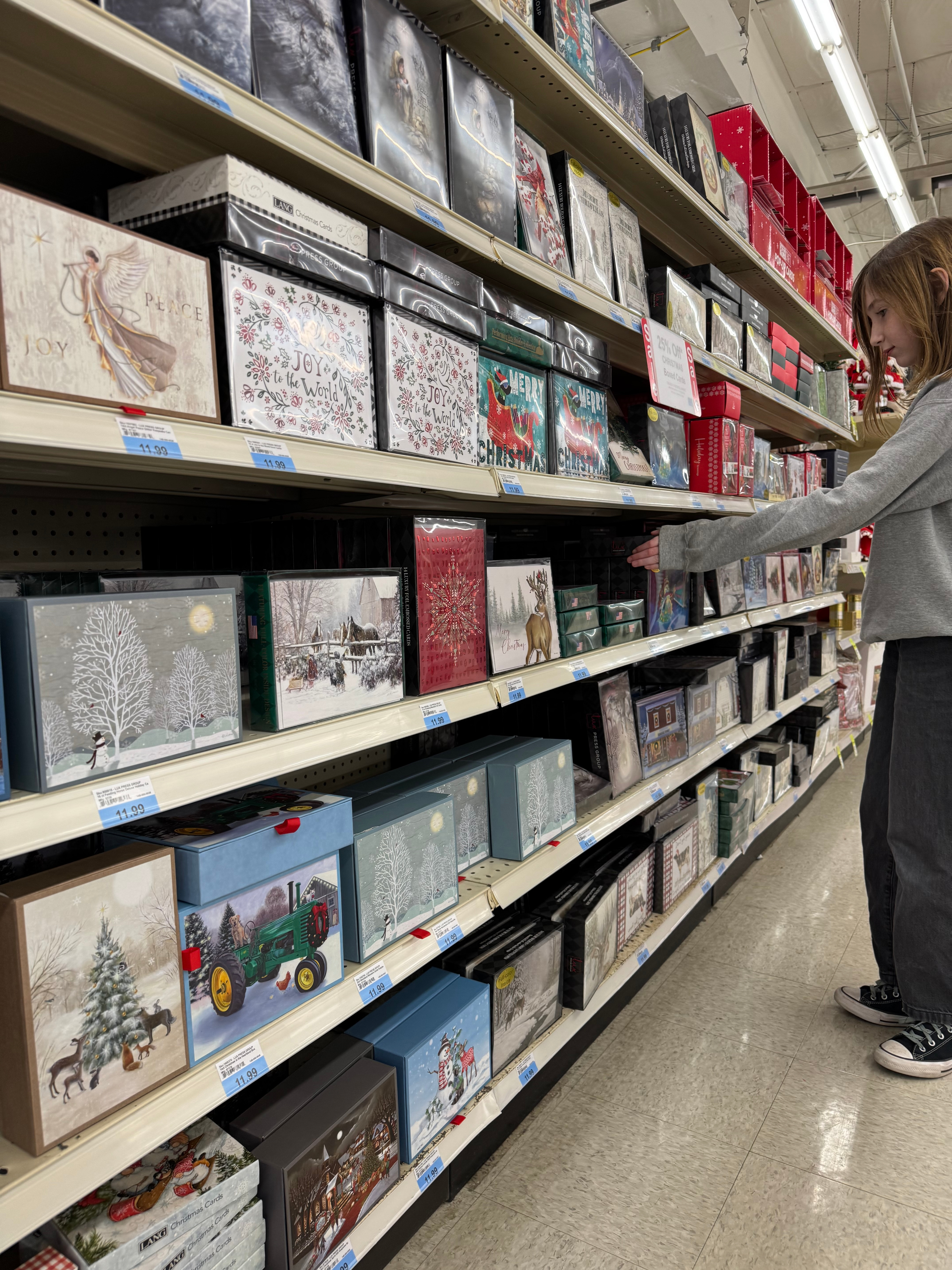 A shopper browsing Lux Press Group boxed Christmas cards on a retail shelf